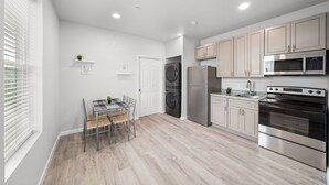 A modern kitchen with a dining area, stainless steel appliances, and light wood flooring.
