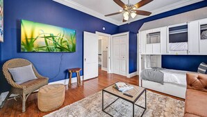 A living room with a ceiling fan, a large painting, a wicker chair, a coffee table, and a sofa.