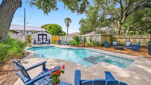 A backyard with a swimming pool, lounge chairs, and a small building.