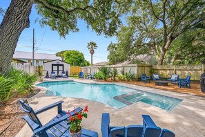 Un jardin avec une piscine, des chaises longues et un petit bâtiment.