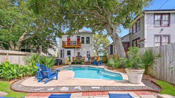 A backyard with a swimming pool, blue lounge chairs, and a wooden deck.