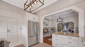 Una cocina moderna con armarios blancos, un refrigerador de acero inoxidable y encimera de granito.