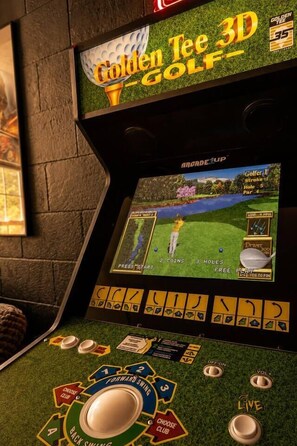 A 3D golf arcade machine with a screen displaying a golf game, control buttons, and a spinning wheel. - Lakefront Home, Hot tub, Fire Pit, Game Room, & Movie Room! (Marion)