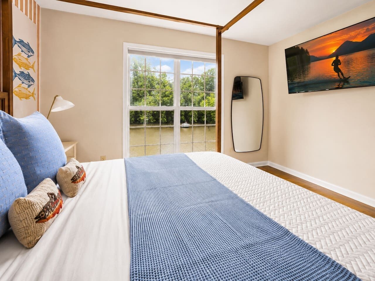 A hotel room with a bed, a view of the outdoors, and a painting on the wall.