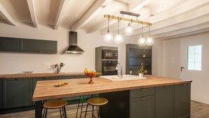 Une cuisine moderne avec un îlot central en bois, des tabourets de bar et des luminaires suspendus.