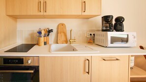 A kitchen with wooden cabinets, a microwave, a coffee maker, and a sink.