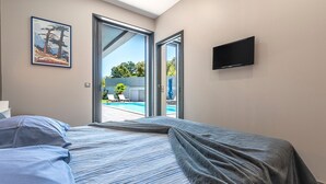 A bedroom with a bed, a TV, and a painting.