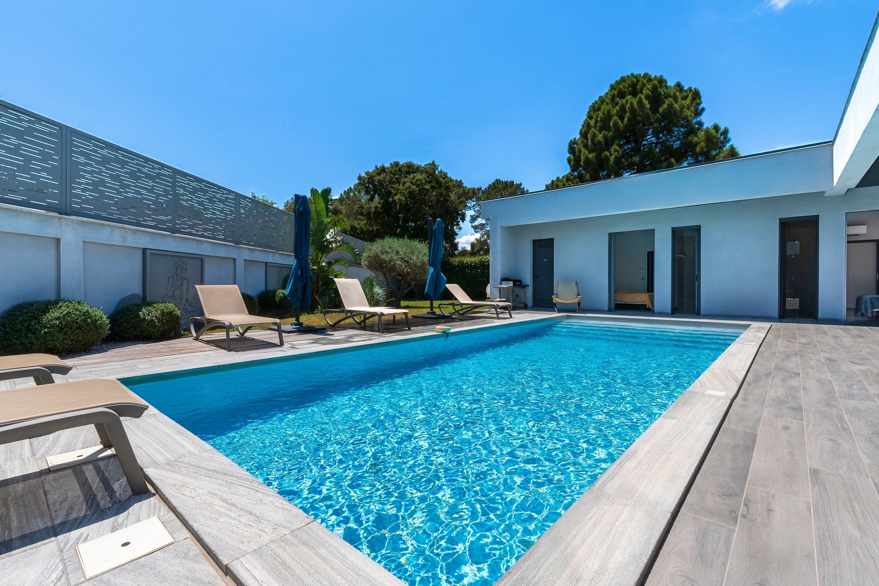 A modern outdoor pool area with lounge chairs and a building in the background.