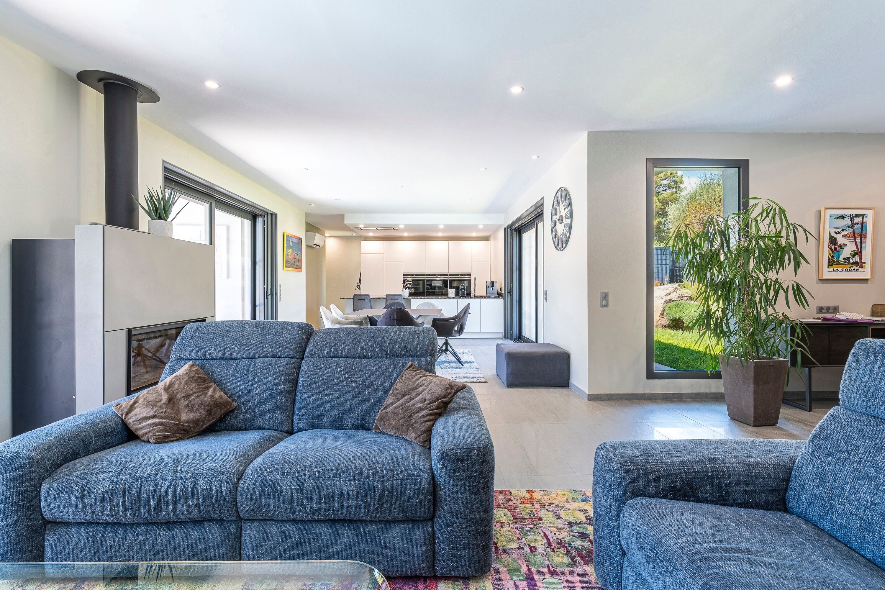 A modern living room with a sofa, a coffee table, and a dining area in the background.