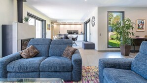 A modern living room with a sofa, a coffee table, and a dining area in the background.