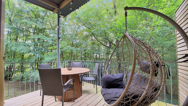 A wooden deck with a hanging chair and a table with chairs. - Les Charmes C24B - Le Val Joly (Eppe-Sauvage)