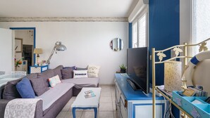 A living room with a sofa, TV, and a desk with a lamp.