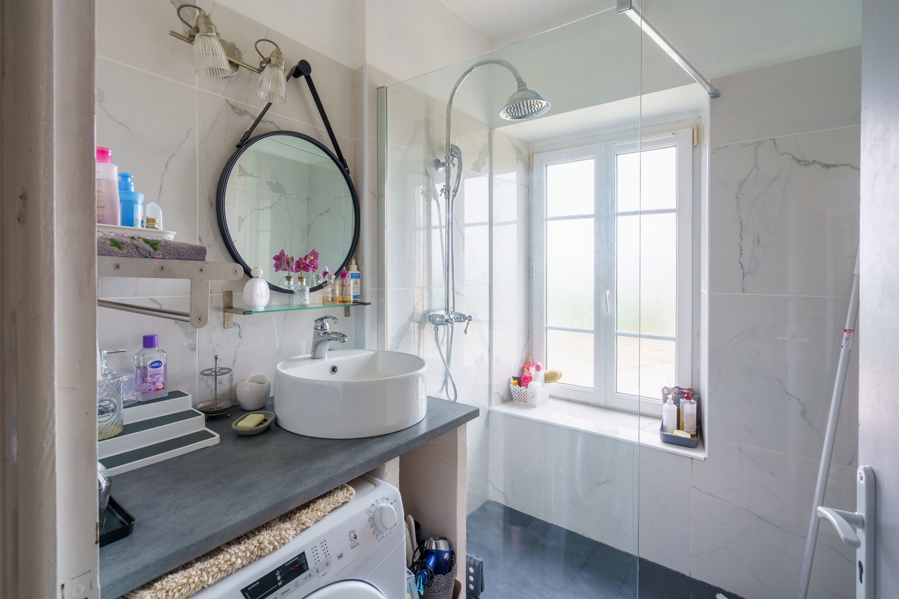 Un bagno moderno con un lavandino grande, uno specchio, una doccia e una finestra.