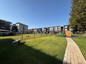 Zona residencial con césped, un sendero pavimentado y una estructura de pared de escalar.