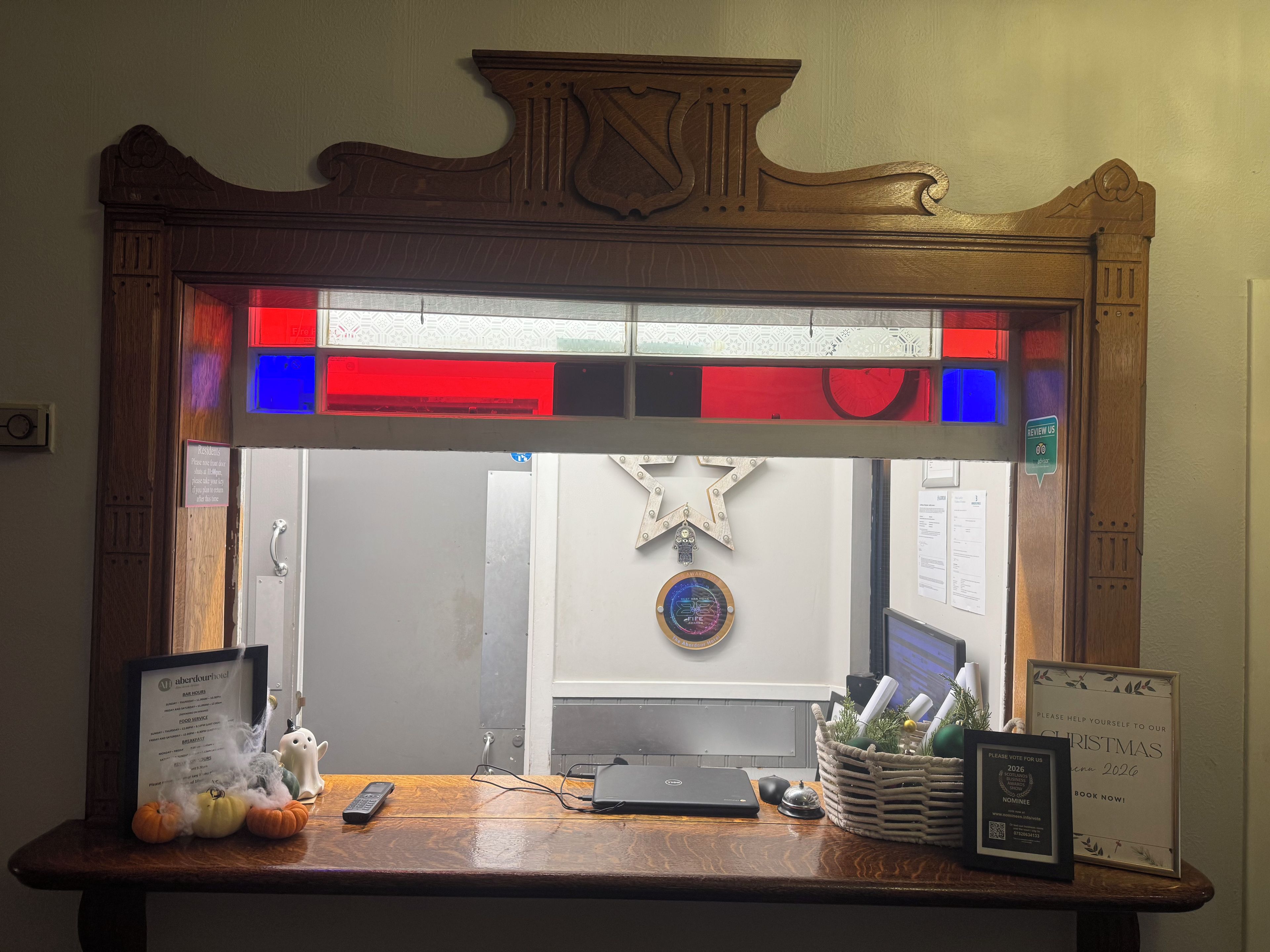 A reception desk with a framed menu, a framed award, and a decorative basket.