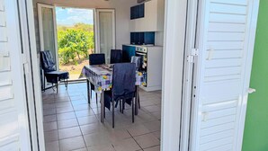 Un comedor con una mesa y sillas, una cocina con armarios y vista a un viñedo por una puerta abierta.