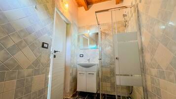 Ein Badezimmer mit Dusche, Waschbecken und gefliesten Wänden.