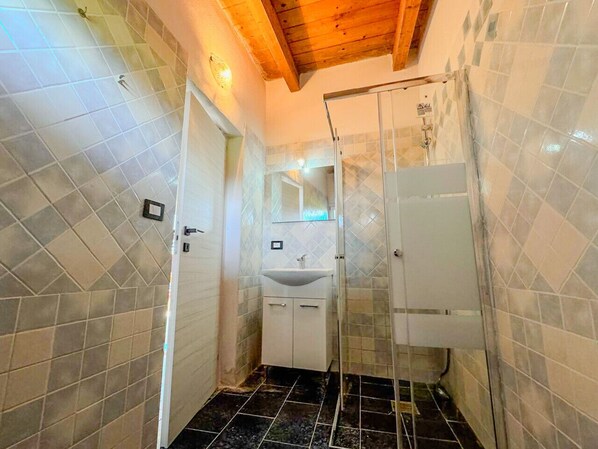 A bathroom with a shower, a sink, and tiled walls.