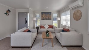 Uma sala de estar moderna com dois sofás, uma mesa de centro e um quadro na parede.