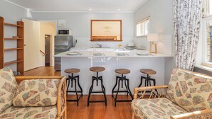 Een moderne keuken met een centraal eiland, barkrukken en een eetgedeelte met gestreepte stoelen.