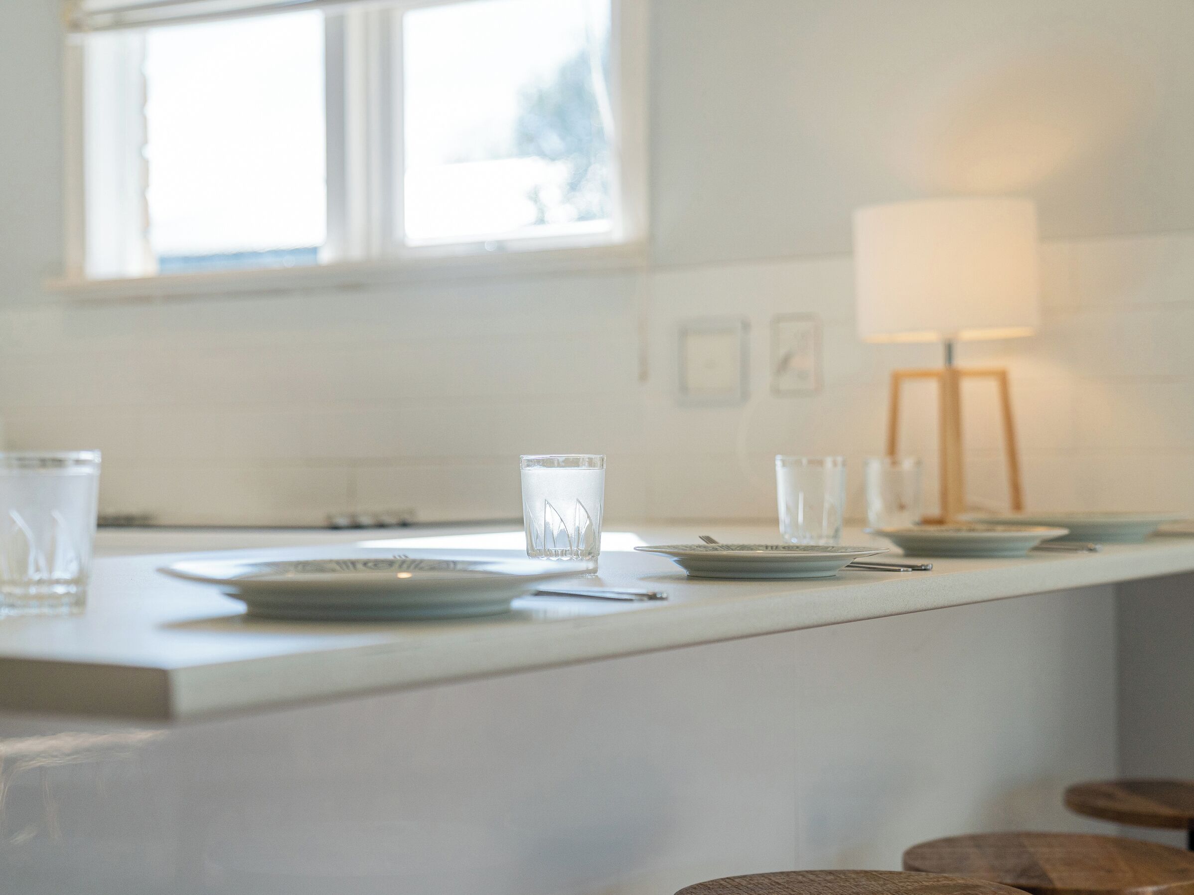 A kitchen with a white countertop, a window, and a lamp.
