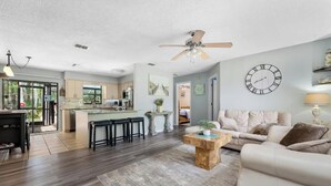 A spacious living area with a sofa, coffee table, and a dining area with stools. - Oasis privacy heated Pool Game room 3 mins Sister Spring (Crystal River)