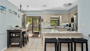A modern kitchen with a large island, bar stools, and a dining area with a view of the outdoors. - Oasis privacy heated Pool Game room 3 mins Sister Spring (Crystal River)