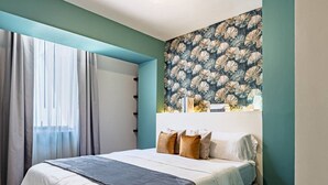 Un dormitorio con cama, cortinas, un papel tapiz floral y una ventana.