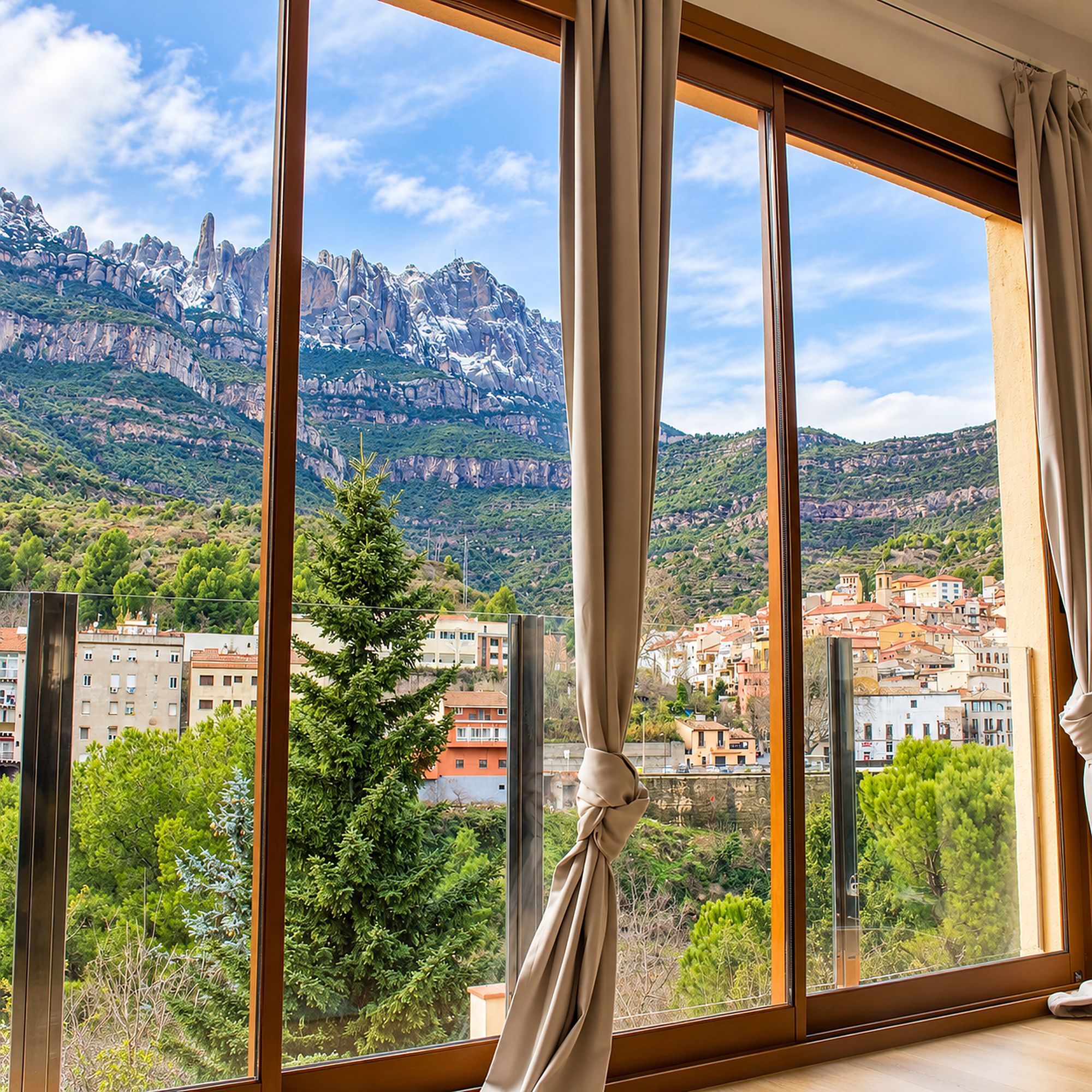 Una habitación con un amplio ventanal que ofrece vistas a un paisaje montañoso y un pueblo en la falda.