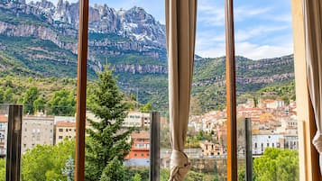 Una habitación con un amplio ventanal que ofrece vistas a un paisaje montañoso y un pueblo en la falda.