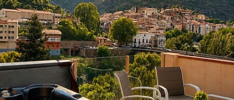 Une terrasse sur le toit avec un jacuzzi, des sièges extérieurs et une vue sur la ville et les montagnes.