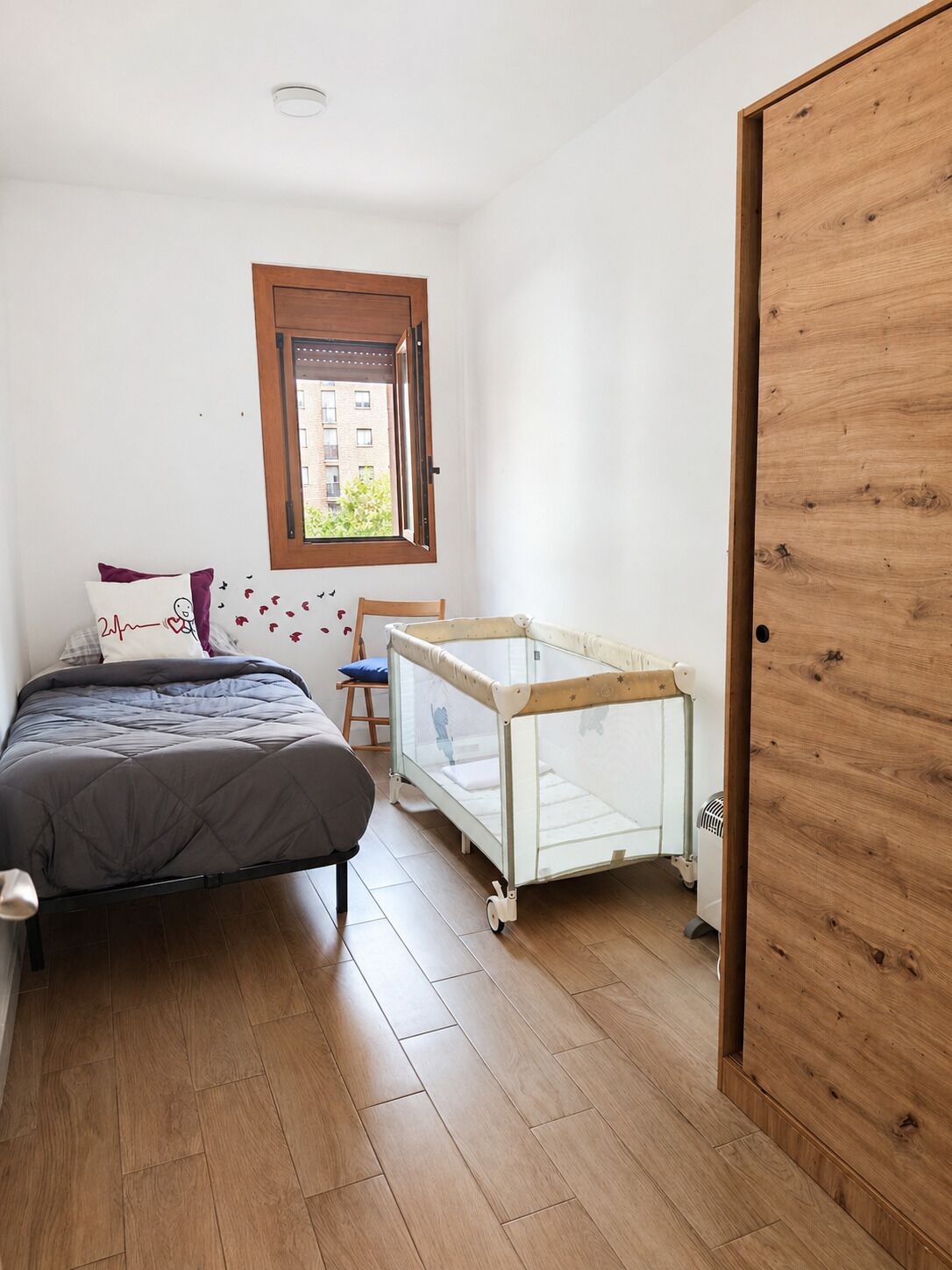 Un dormitorio con cama, cuna, ventana y puerta.