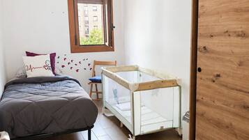 Un dormitorio con cama, cuna, ventana y puerta.