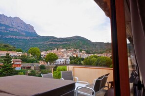 A balcony with a table and chairs, overlooking a town with buildings and a mountain in the background. - Private penthouse with jacuzzi, terrace and Montserrat views (Monistrol de Montserrat)
