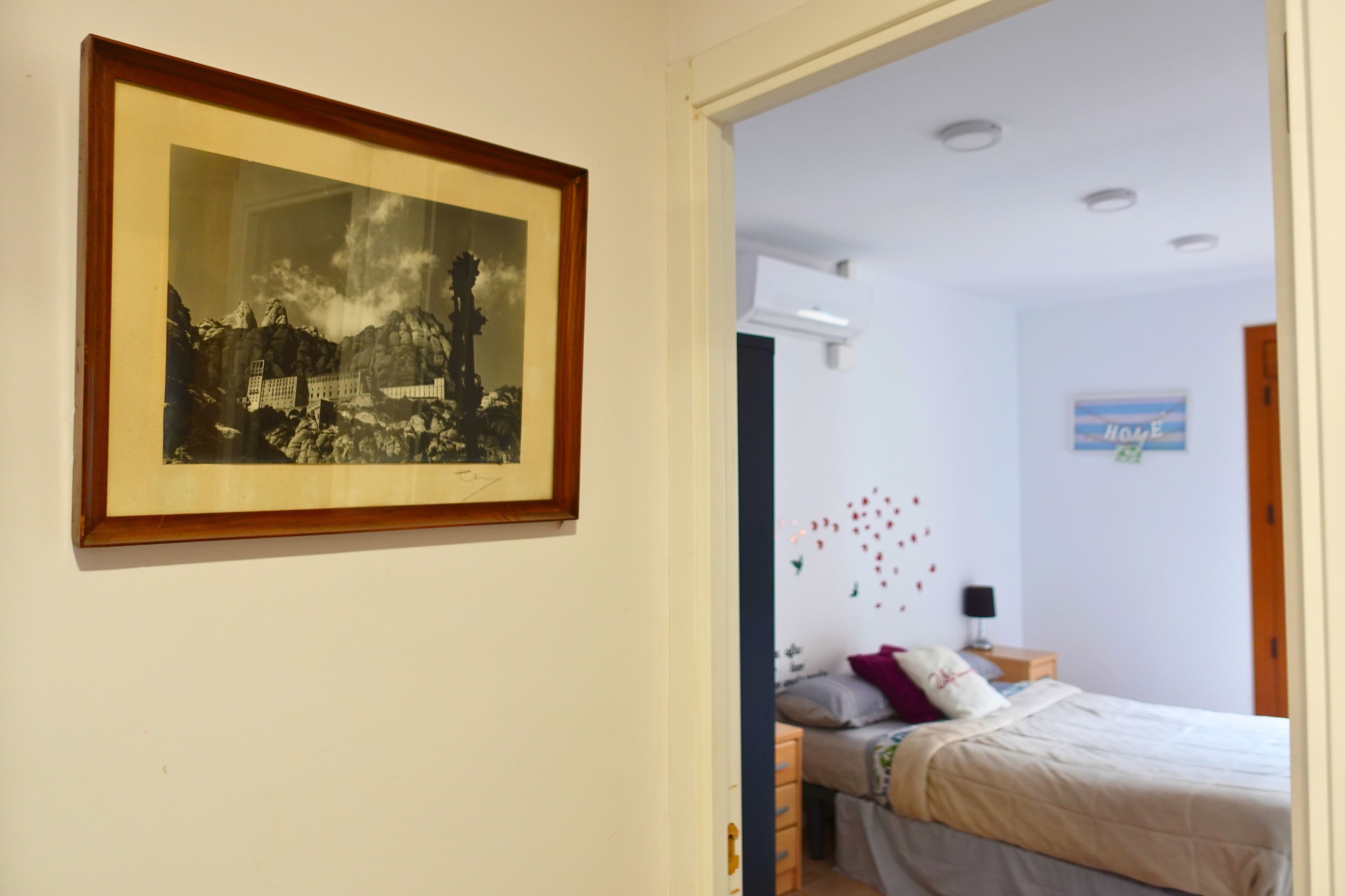 Une pièce comprenant un lit, une table de chevet, un tableau encadré au mur et un élément décoratif mural.