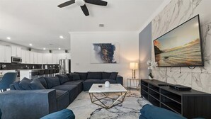 Una sala de estar moderna con un sofá modular, una mesa de centro y un televisor sobre una pared de mármol.