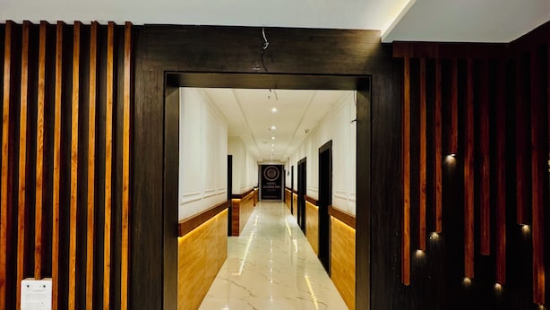 A hotel corridor with wooden paneling, marble flooring, and recessed lighting. - Hotel Ellora Inn Sultanpur (Sultanpur)