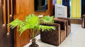 A modern living room with a flat-screen TV mounted on a wooden wall, a ceiling fan, and a potted plant. - Hotel Ellora Inn Sultanpur (Sultanpur)