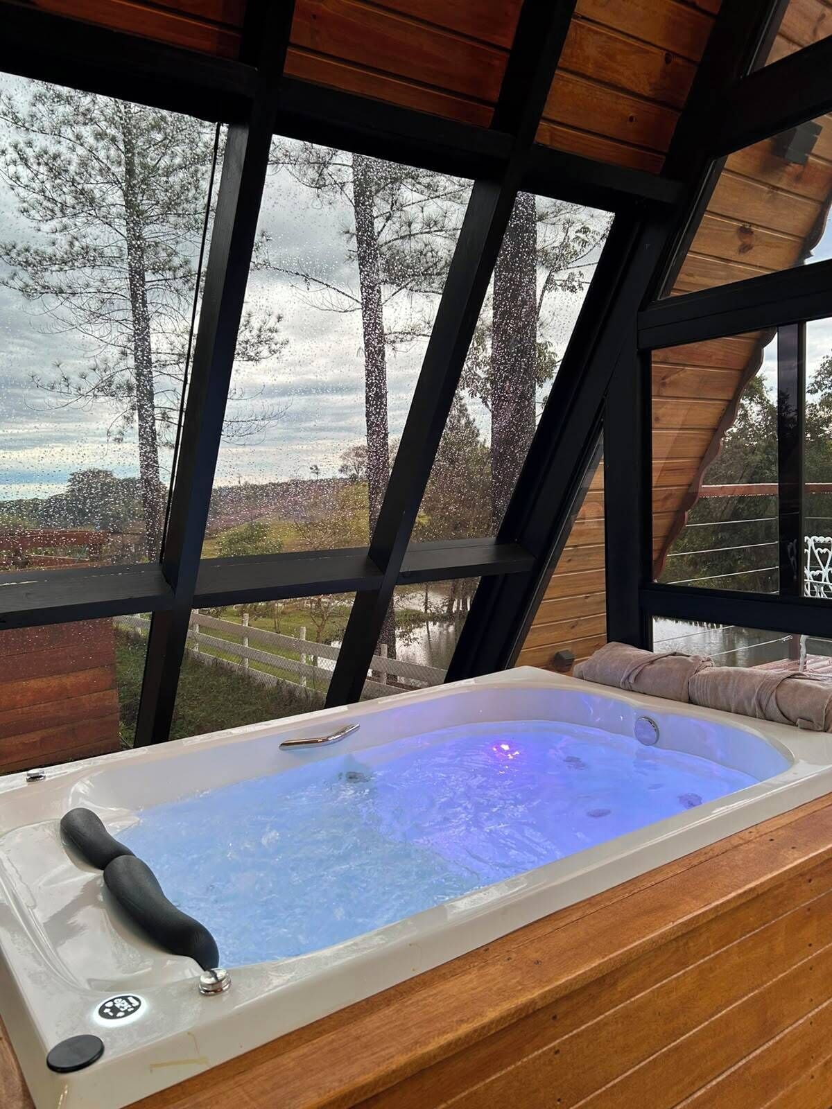 A hot tub with a view of a snowy landscape through large windows.