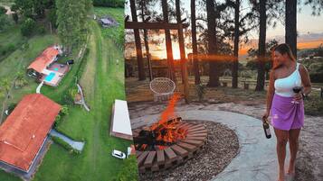 A house with a swimming pool, a fire pit, and a view of the sunset.
