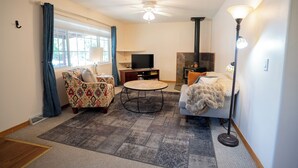A cozy living room with a TV, a fireplace, and a ceiling fan. - 4-Bedroom Home with Fenced Backyard (Lander)