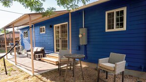 A blue house with a covered patio, outdoor seating, and a power box on the wall. - 4-Bedroom Home with Fenced Backyard (Lander)