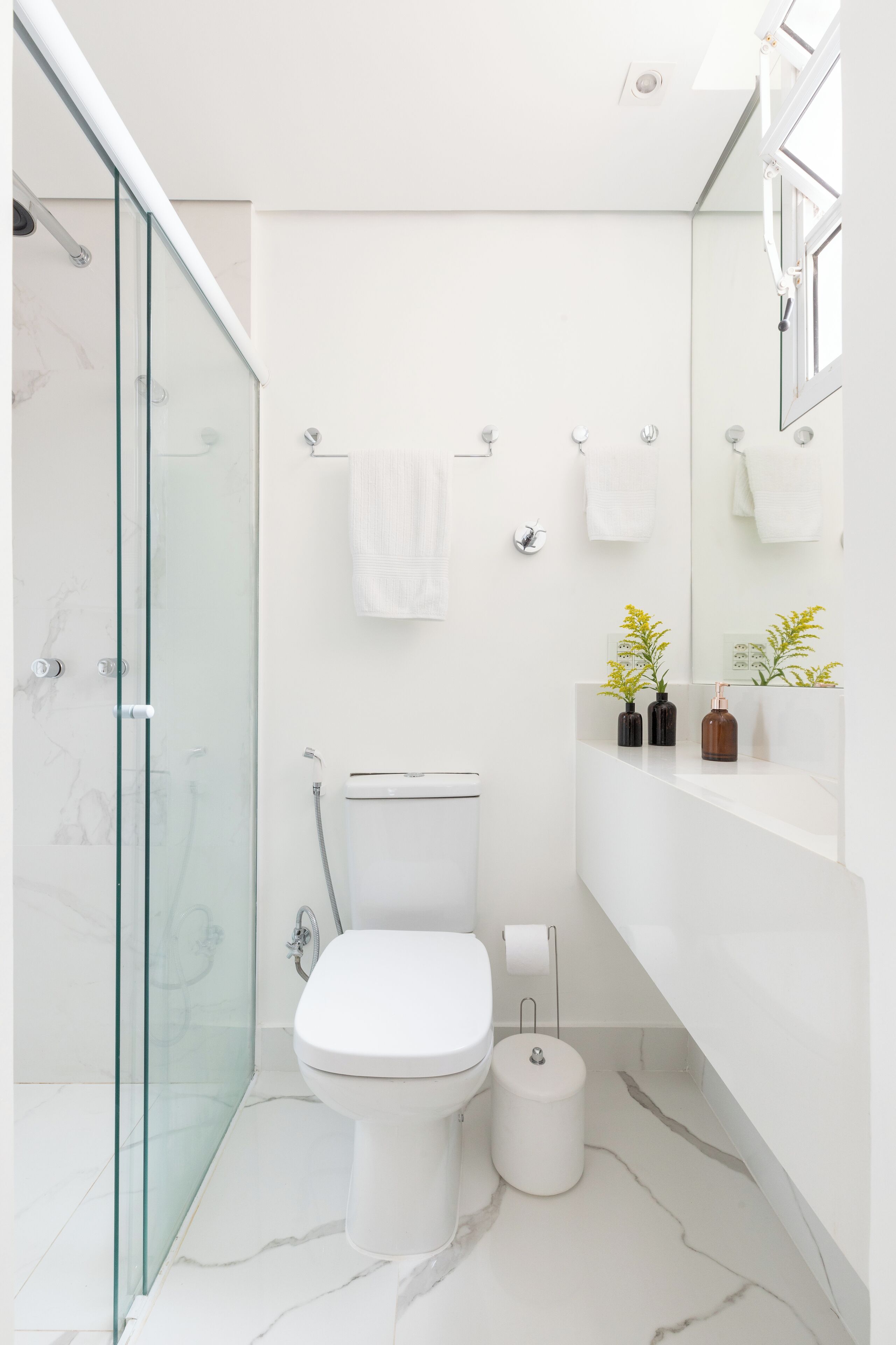 Un baño moderno con cabina de ducha de vidrio, inodoro blanco y suelo de baldosas de mármol.