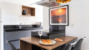 Une cuisine moderne avec une table à manger en bois, des chaises noires et un tableau encadré accroché au mur.