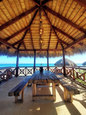 A wooden pavilion with a thatched roof overlooking a beach. - Serendipia Hotel (Nizao)
