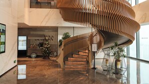 Un interior moderno con una escalera de madera curva, un árbol de Navidad y una barandilla de vidrio.