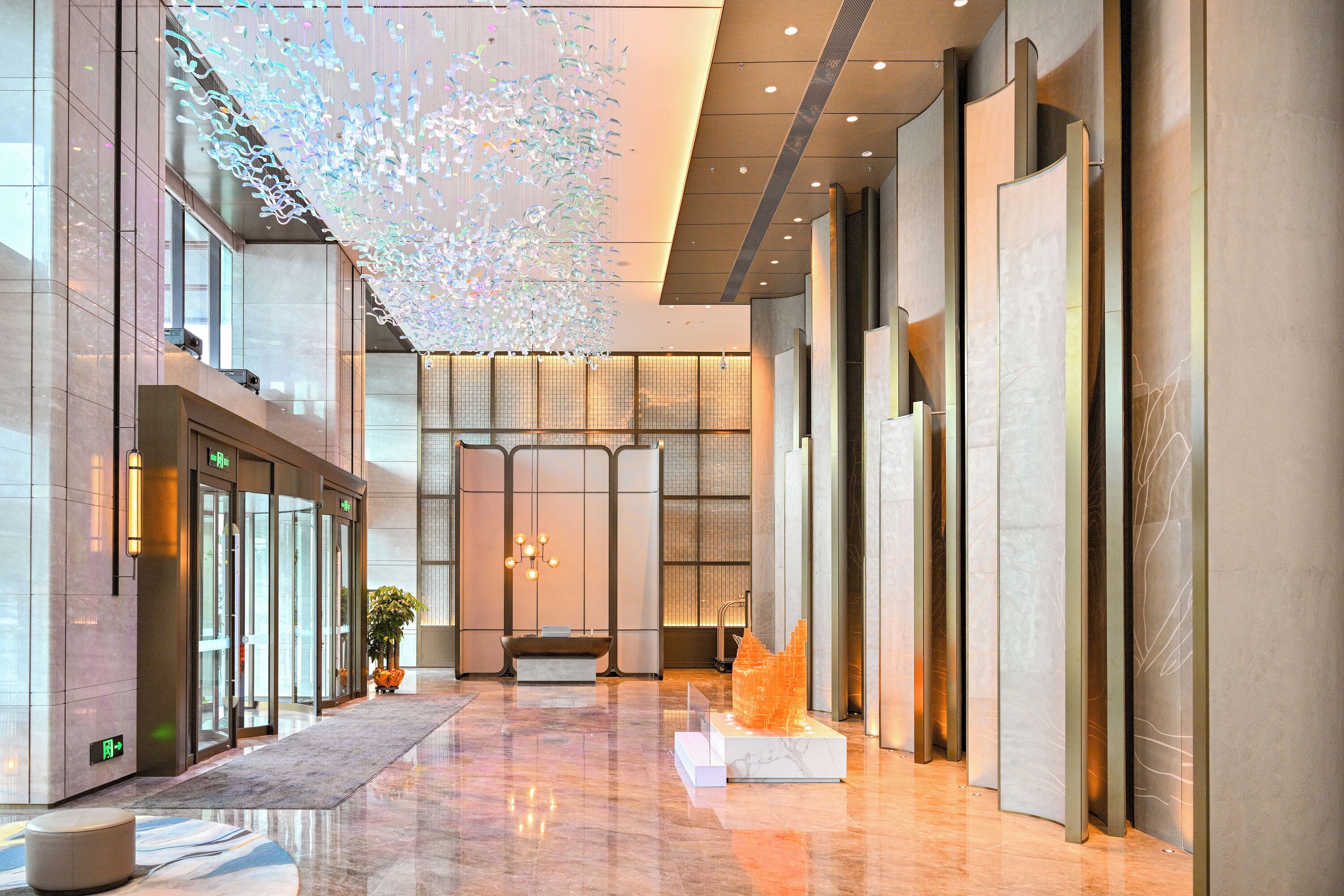 Um lobby moderno com portas de vidro, balcão de recepção e uma instalação luminosa decorativa.