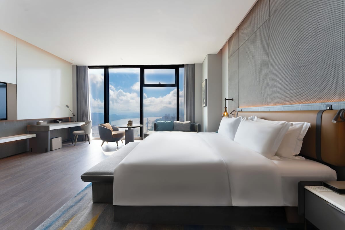 Una habitación de hotel moderna con una cama grande, un escritorio y vistas a la ciudad.