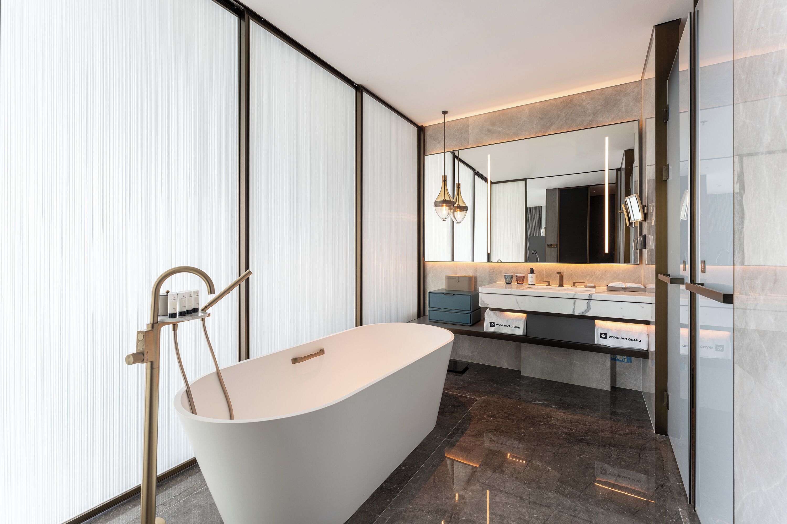 Un baño moderno con una bañera independiente, un espejo grande y un tocador con encimera.