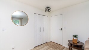 A hallway with a mirror, a ceiling light fixture, a door, and a small table with a plant. - Walk to DT I King I Keyless Entry I Garage I W/D (Fargo)